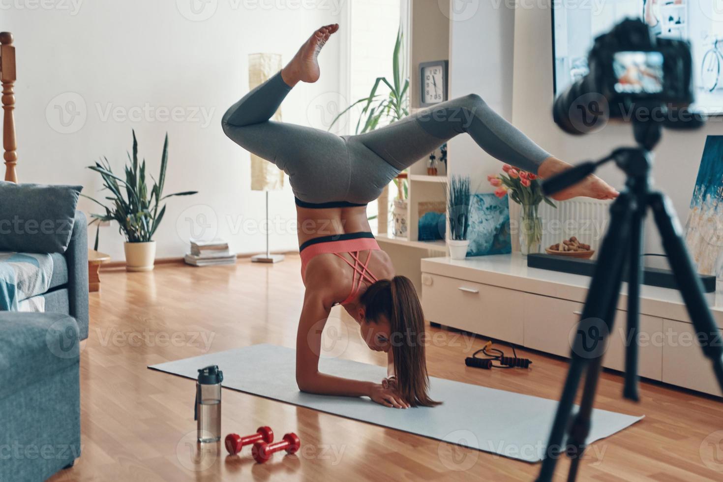 jeune femme flexible en vêtements de sport debout sur les mains tout en faisant une vidéo sur les réseaux sociaux photo