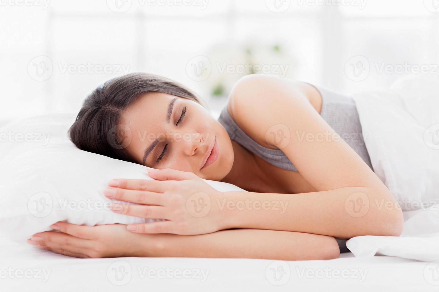 beaux rêves. belle jeune femme allongée dans son lit et gardant les yeux fermés tout en étant recouverte d'une couverture photo