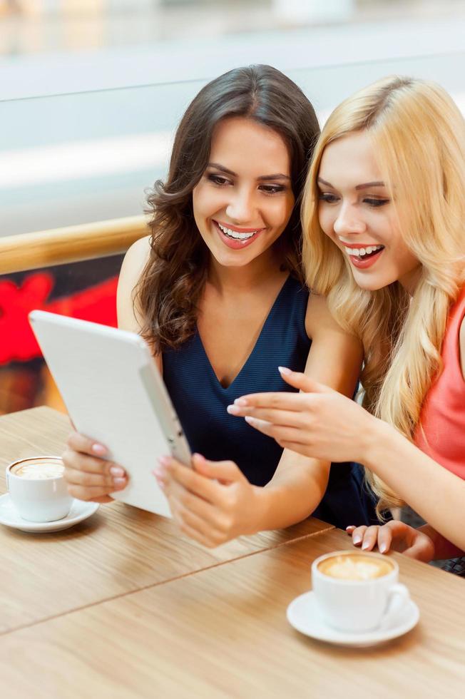 amis heureux au restaurant. deux jeunes femmes s'amusent en buvant un café au restaurant photo