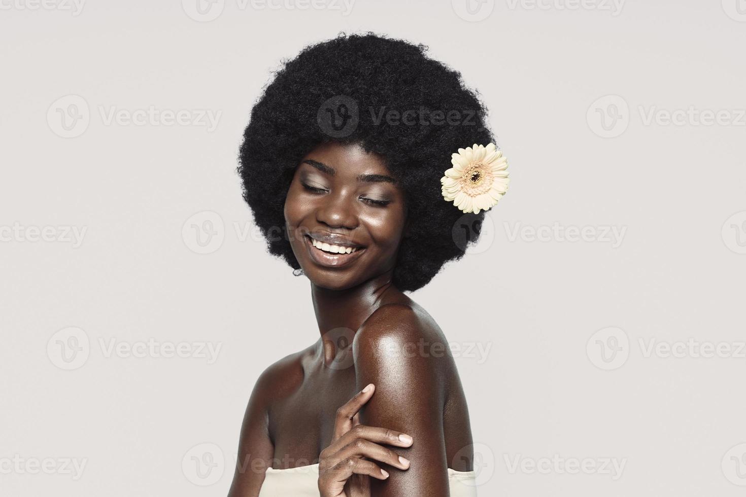 portrait de la belle jeune femme africaine touchant l'épaule et souriant photo