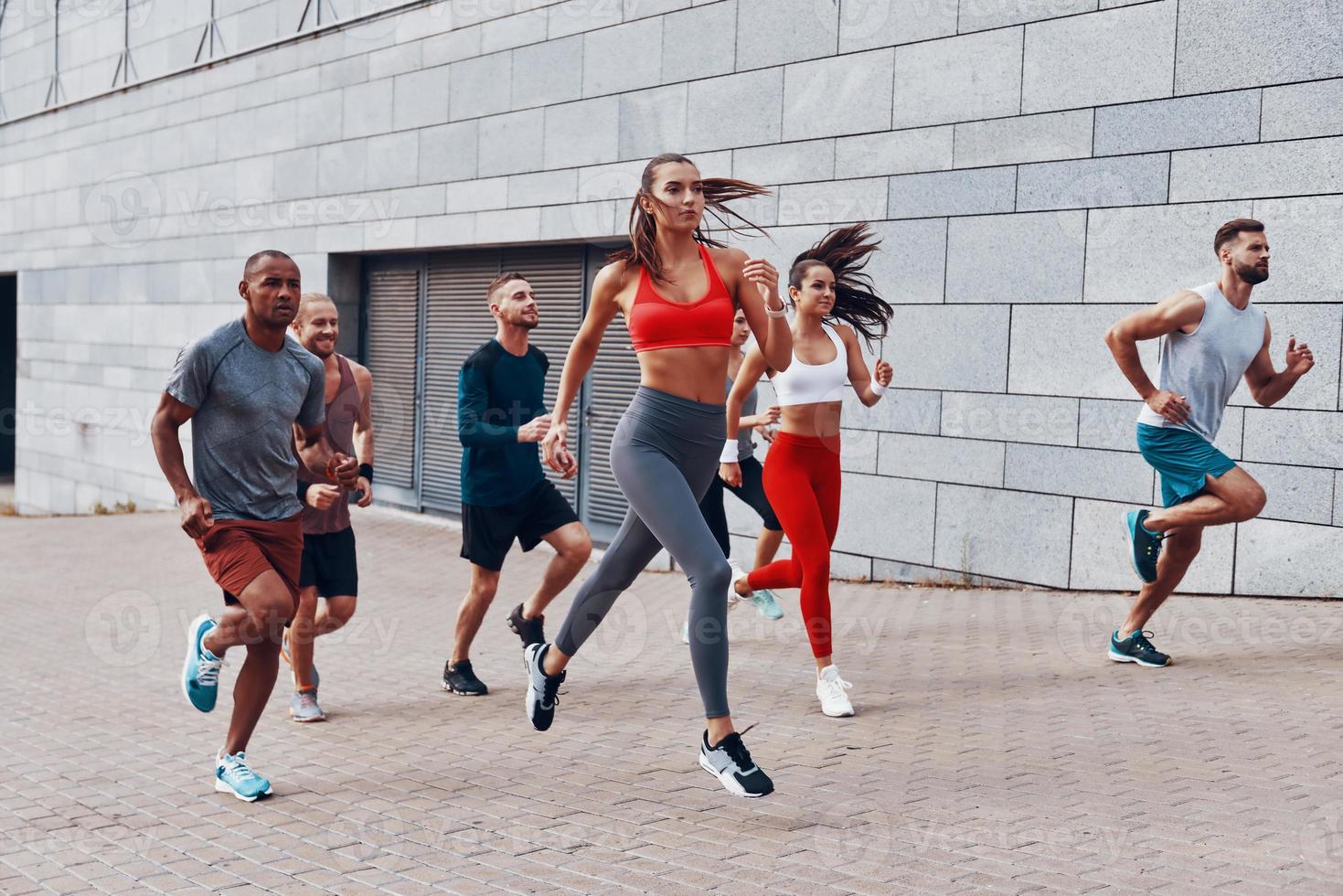 toute la longueur des jeunes en vêtements de sport faisant du jogging tout en faisant de l'exercice sur le trottoir à l'extérieur photo