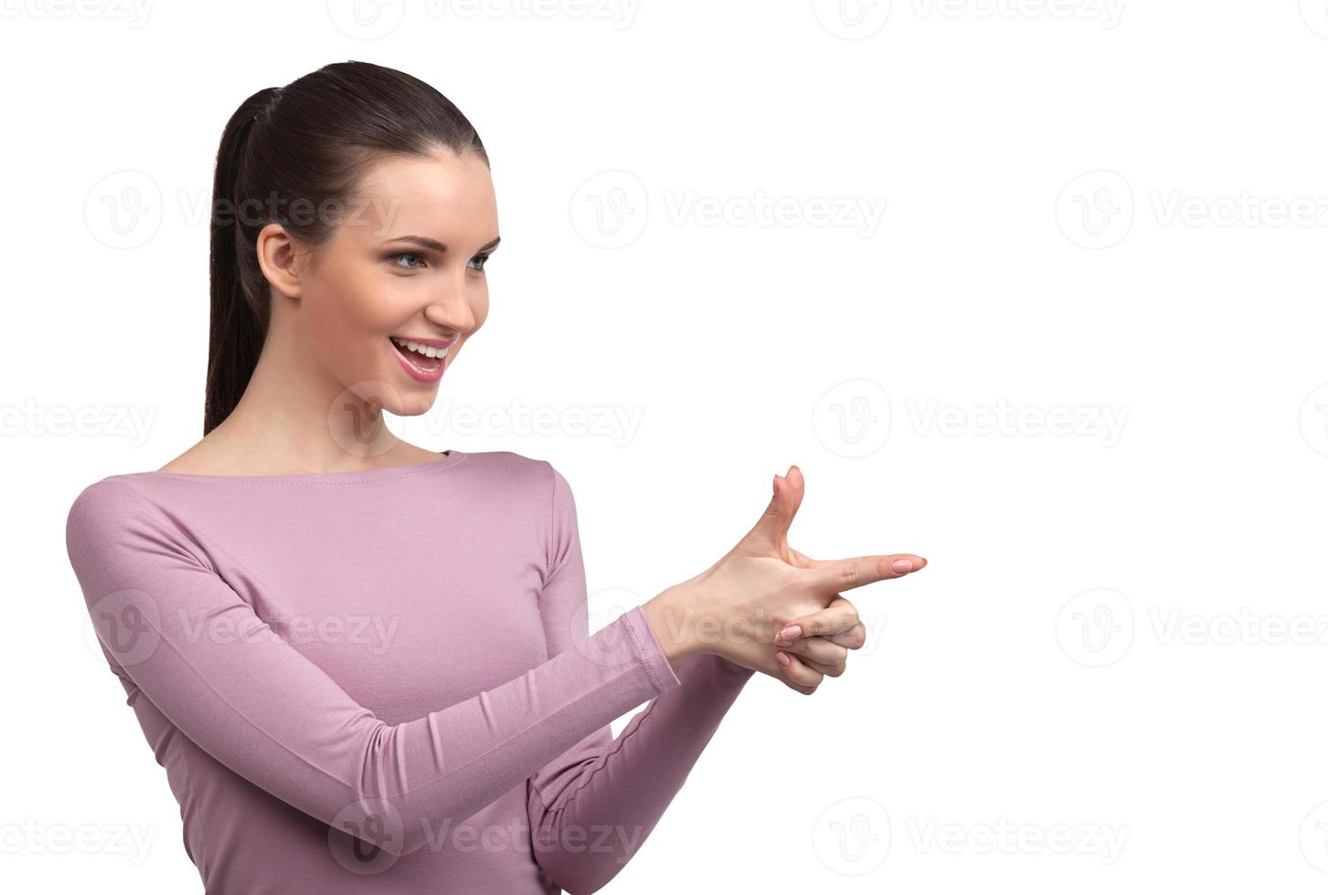 elle obtient ce qu'elle veut. jolie jeune femme faisant une arme à feu des doigts et pointant vers l'extérieur tout en se tenant isolé sur blanc photo