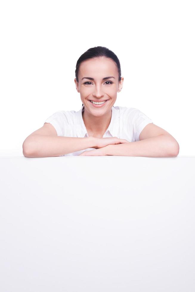 se penchant à l'espace de copie. belle jeune femme se penchant à l'espace de copie et souriant debout isolé sur blanc photo