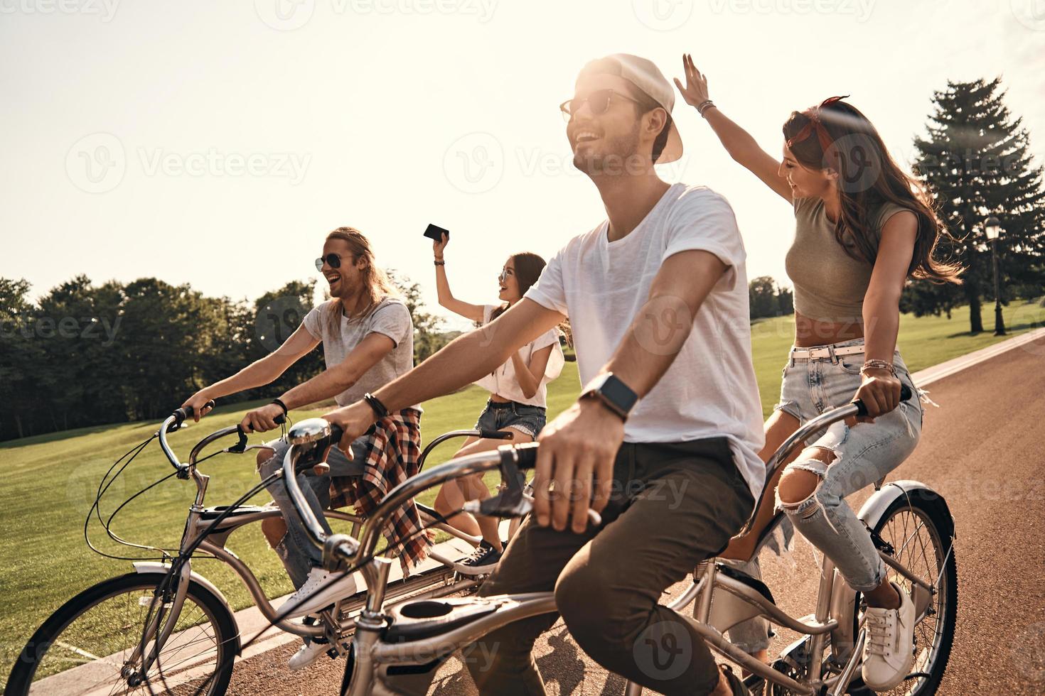 simplement s'amuser. groupe de jeunes gens heureux en tenue décontractée prenant selfie et souriant tout en faisant du vélo ensemble à l'extérieur photo
