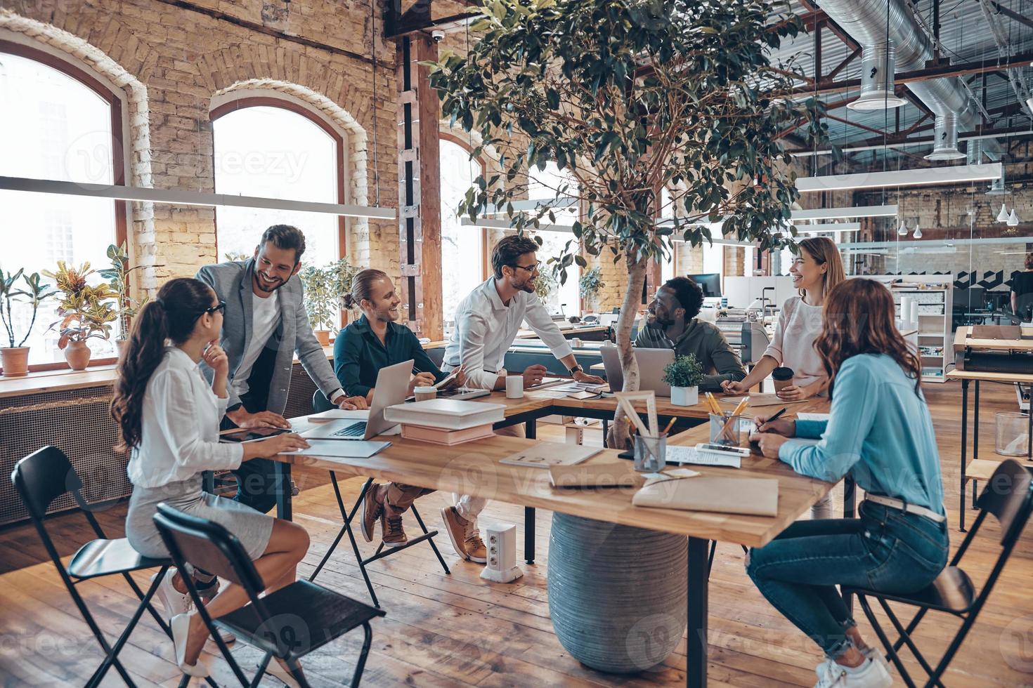 groupe de jeunes gens modernes en vêtements décontractés intelligents communiquant et utilisant des technologies modernes tout en travaillant au bureau photo