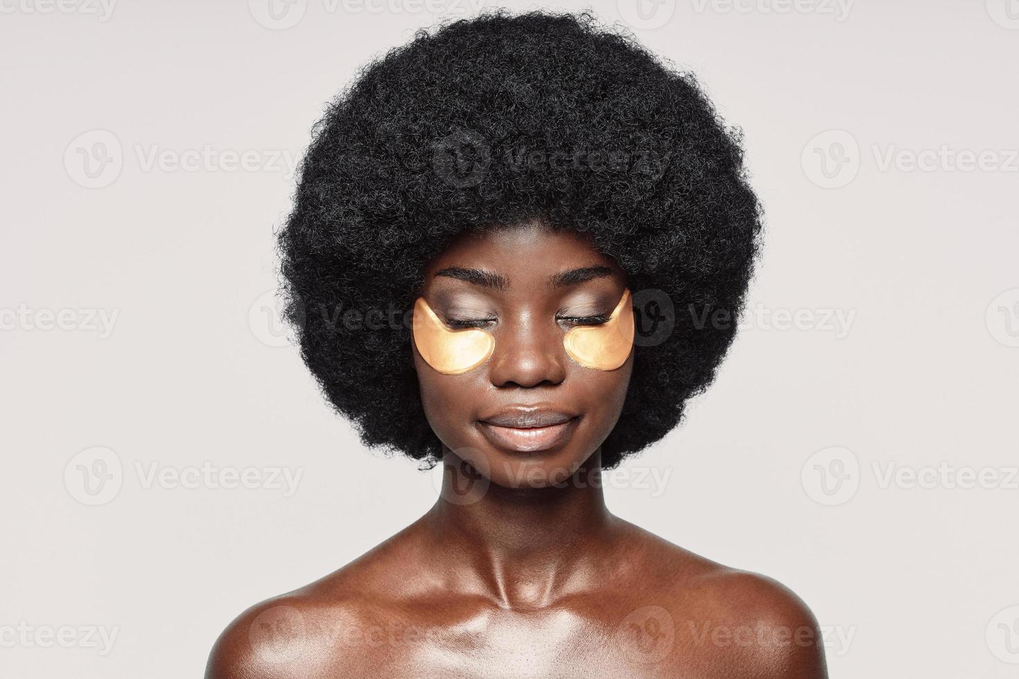portrait d'une belle jeune femme africaine avec des taches près des yeux debout sur fond gris photo