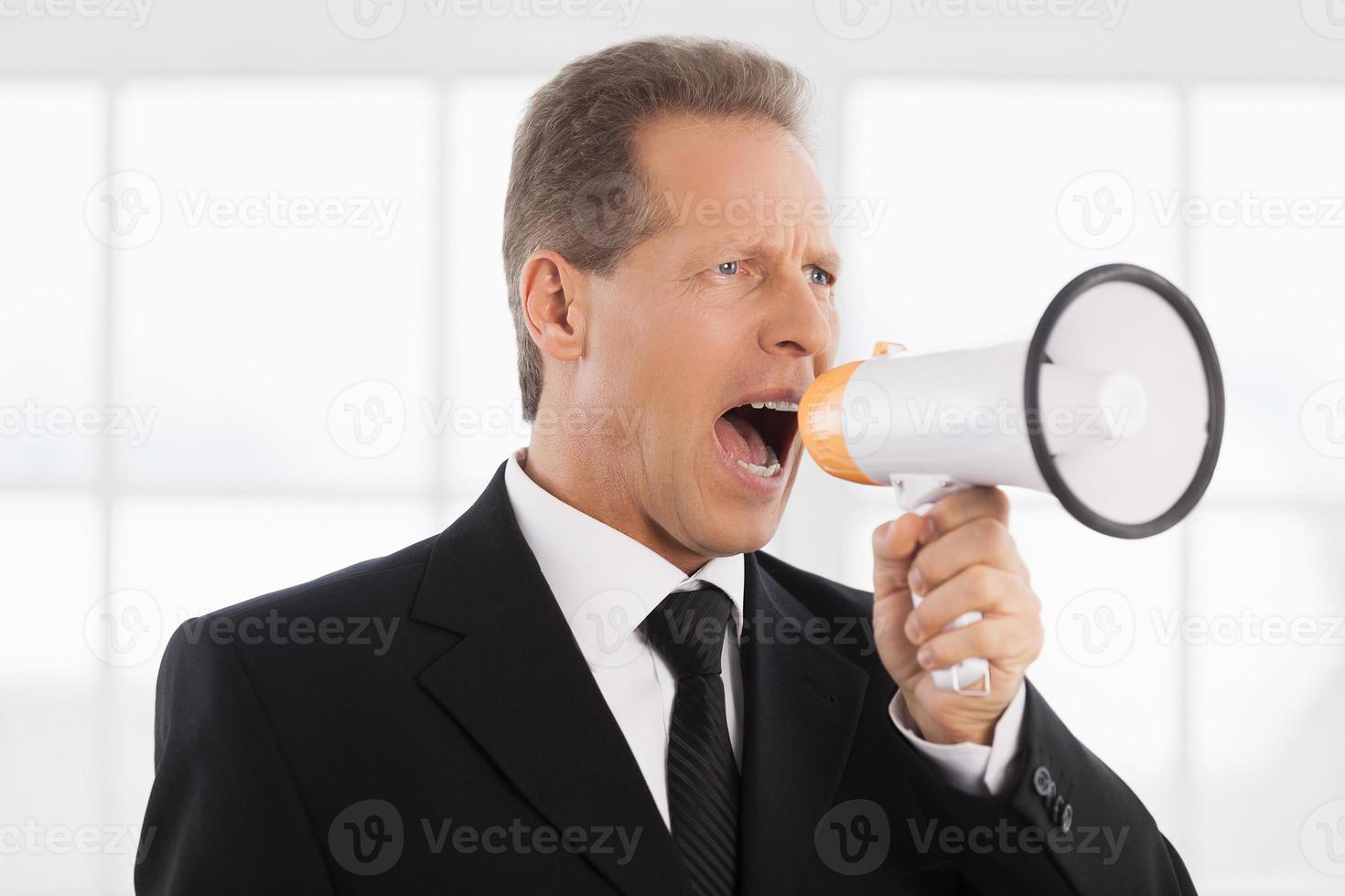 homme d'affaires avec mégaphone. portrait d'un homme mûr confiant en tenues de soirée criant au mégaphone tout en se tenant près de la fenêtre photo