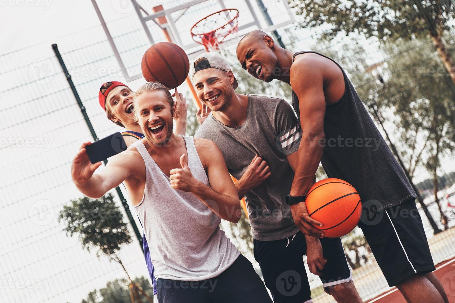 créer des souvenirs heureux. groupe de jeunes hommes en vêtements de sport prenant selfie et souriant tout en se tenant à l'extérieur photo