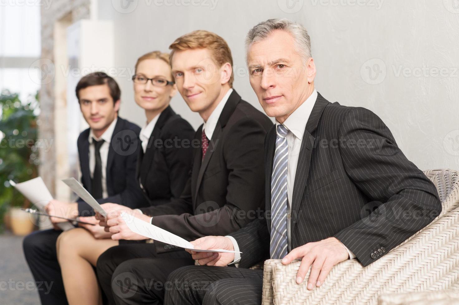 en attente d'un entretien d'embauche. quatre personnes en tenues de soirée faisant la queue et souriant photo