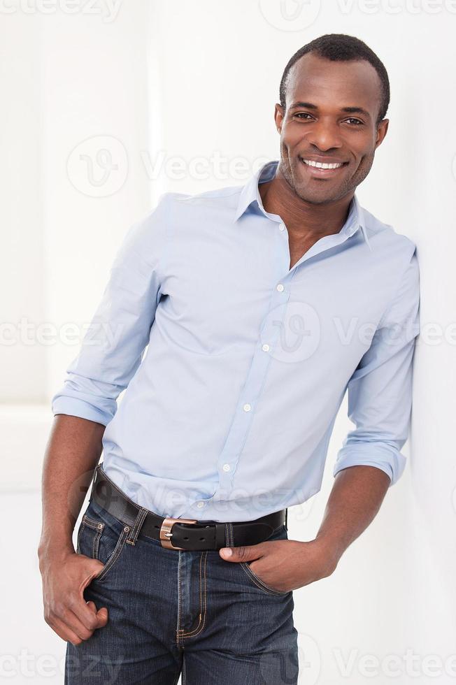 homme qui a réussi. gai jeune homme noir appuyé au mur et souriant à la caméra photo