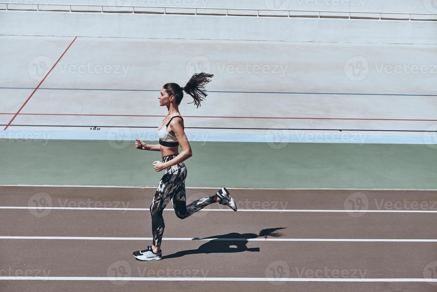 le sport est le chemin de sa vie. vue de dessus pleine longueur d'une jeune femme en vêtements de sport faisant du jogging tout en faisant de l'exercice à l'extérieur photo