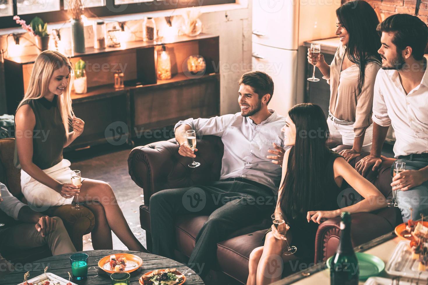 moment insouciant entre amis. vue de dessus de jeunes gens joyeux appréciant la nourriture et les boissons tout en passant du bon temps dans des chaises confortables à la maison ensemble photo