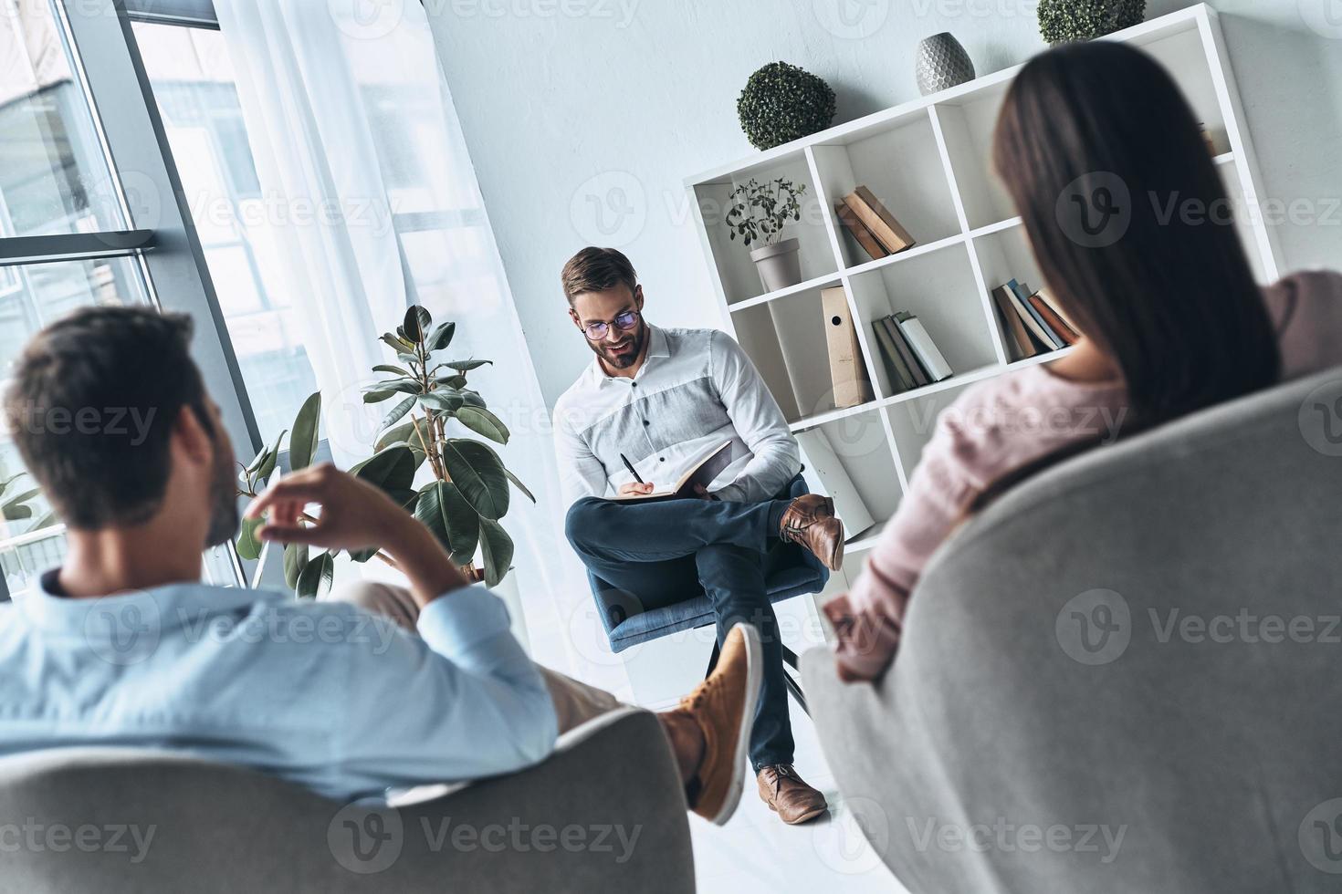 jeune professionel. jeune couple marié parlant assis sur la séance de thérapie avec un psychologue photo