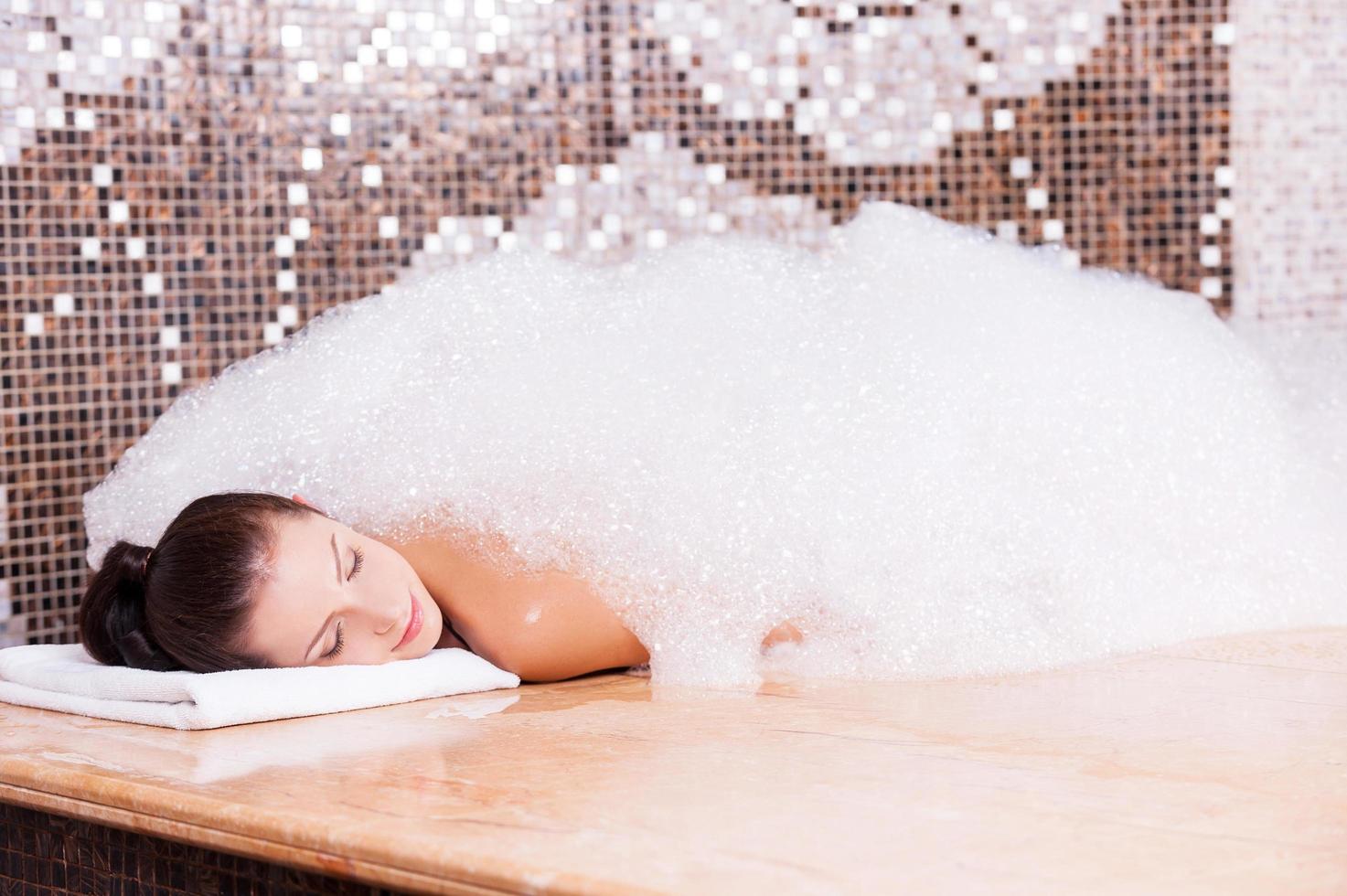 plaisir savonneux. belle jeune femme relaxante dans un bain turc avec de la mousse photo