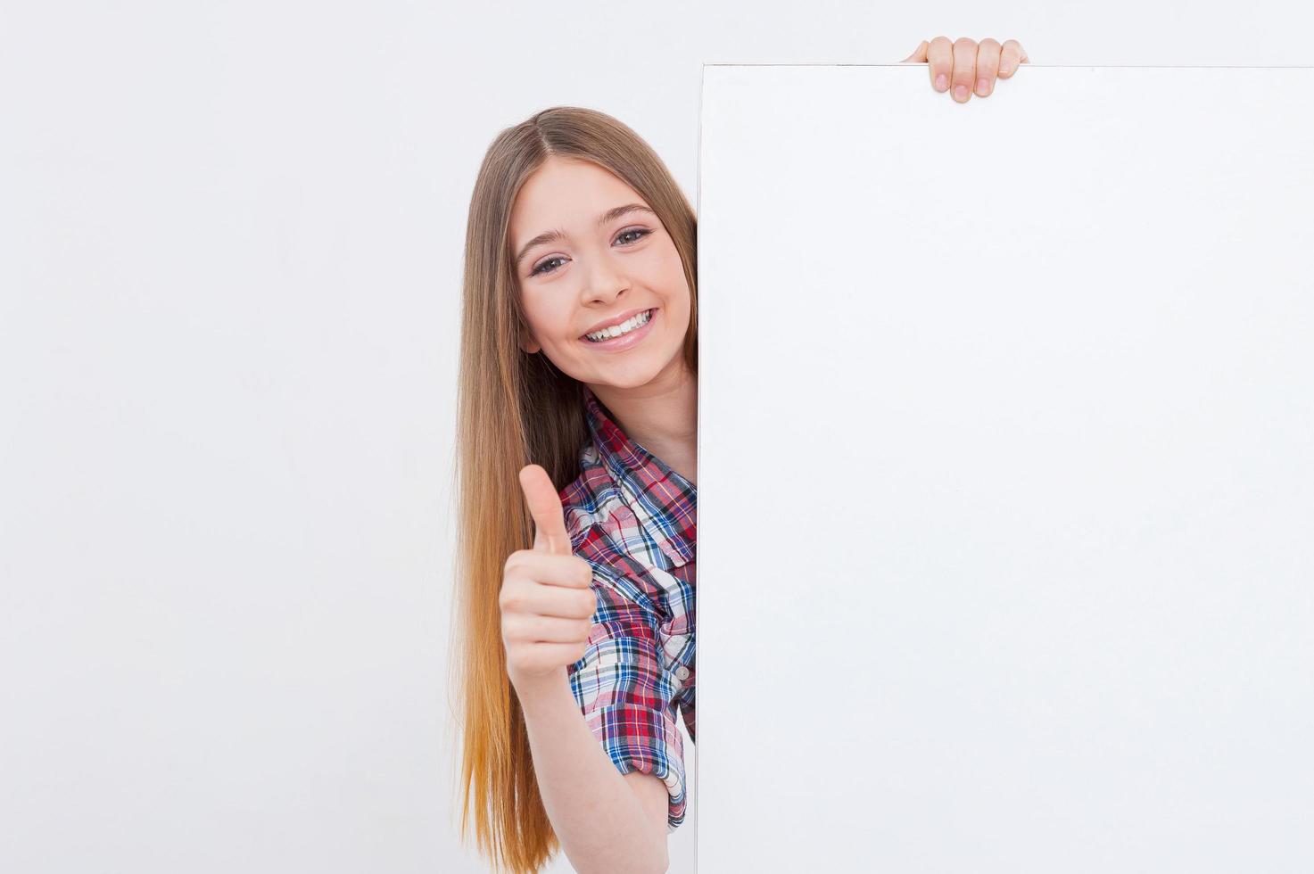 pouce vers le haut pour le succès. adolescente joyeuse se penchant sur l'espace de copie et montrant son pouce vers le haut tout en étant isolée sur blanc photo