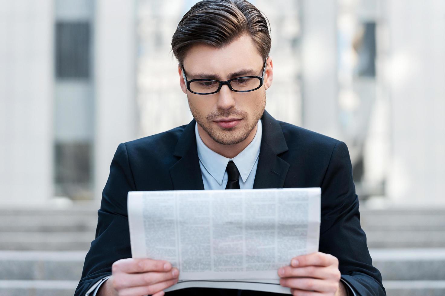 nouvelles du matin. un jeune homme d'affaires lisant un journal à l'extérieur photo