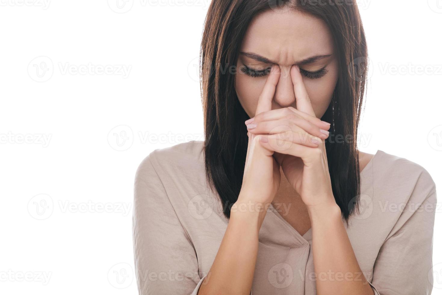 se sentir fatigué et stressé. jeune femme frustrée massant son nez et gardant les yeux fermés en se tenant debout sur fond blanc photo