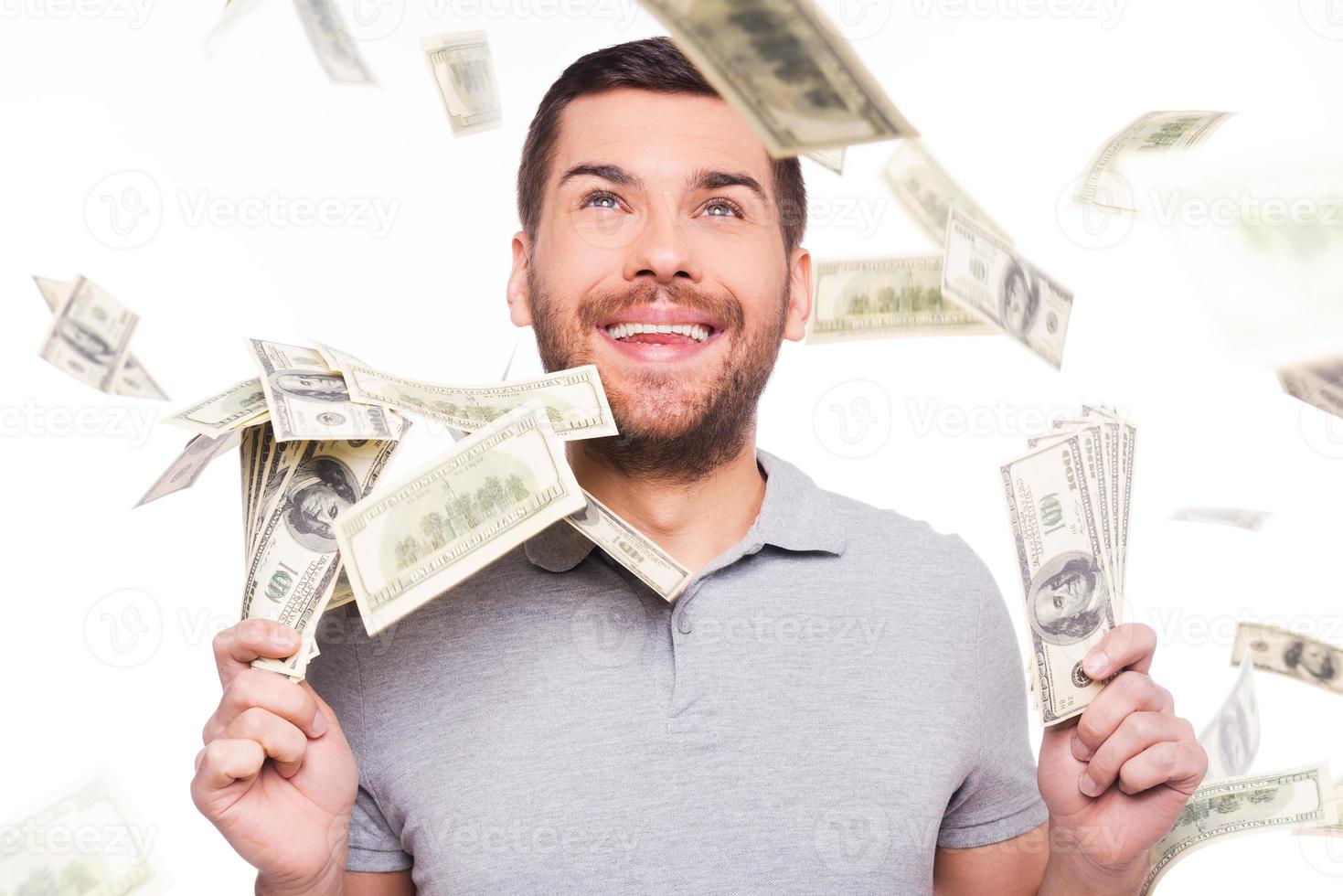 l'argent du ciel. heureux jeune homme levant les yeux et tenant le papier-monnaie en se tenant debout sur fond blanc et le papier-monnaie tombant photo
