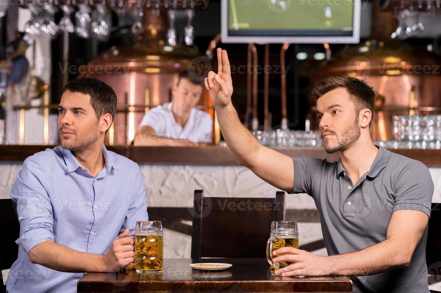 serveur deux jeunes hommes assis dans un bar tandis que l'un d'eux appelle un serveur photo