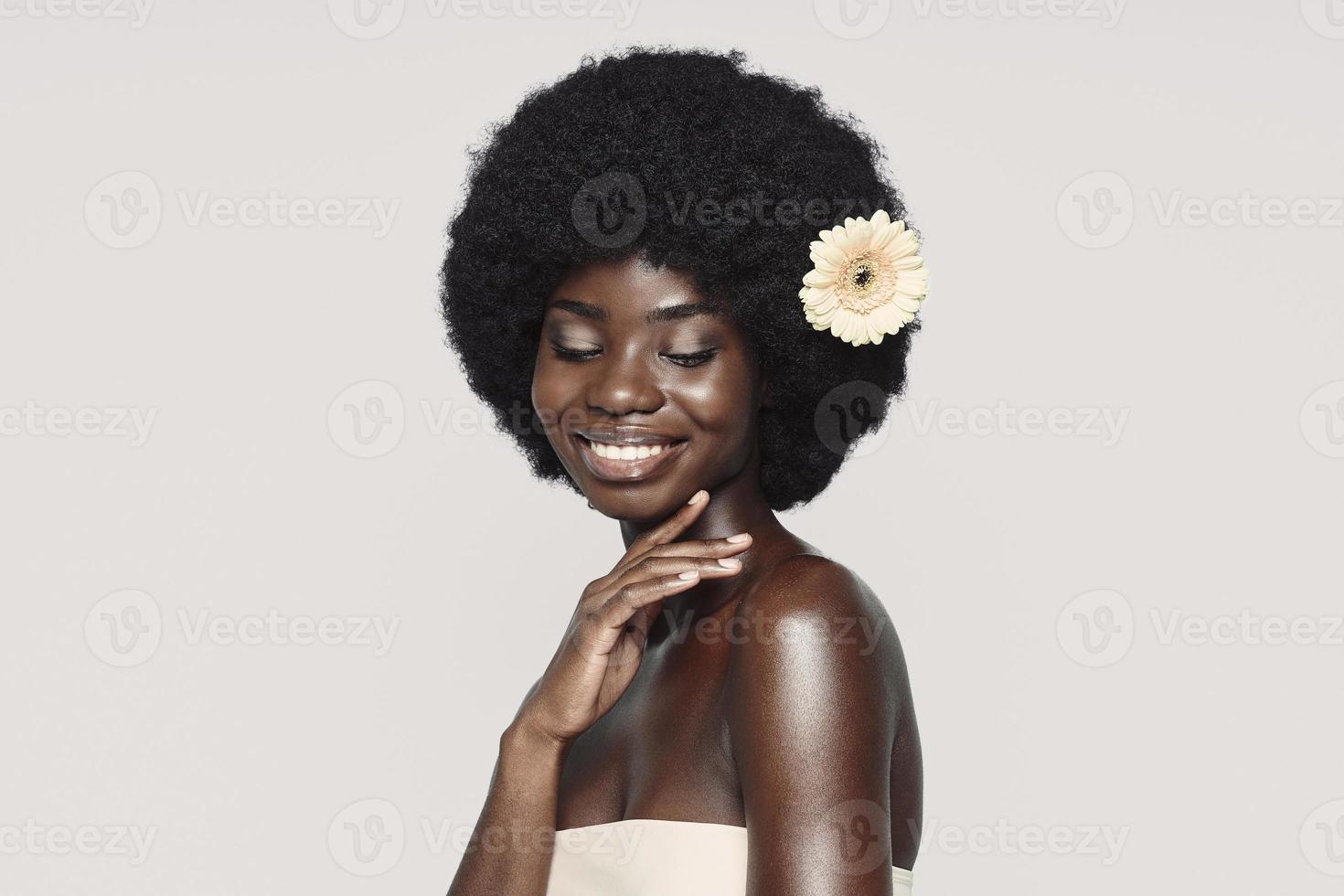 portrait de la belle jeune femme africaine touchant l'épaule et souriant photo