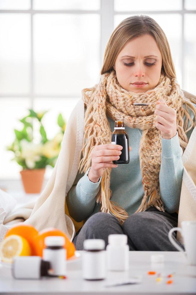 prendre des médicaments. jeune femme prenant des médicaments assise dans son lit dans son appartement photo