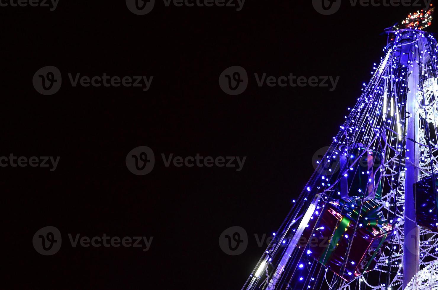 fragment de l'arbre du nouvel an. beaucoup de lumières rondes de couleur bleue sont situées sur un cadre conique photo