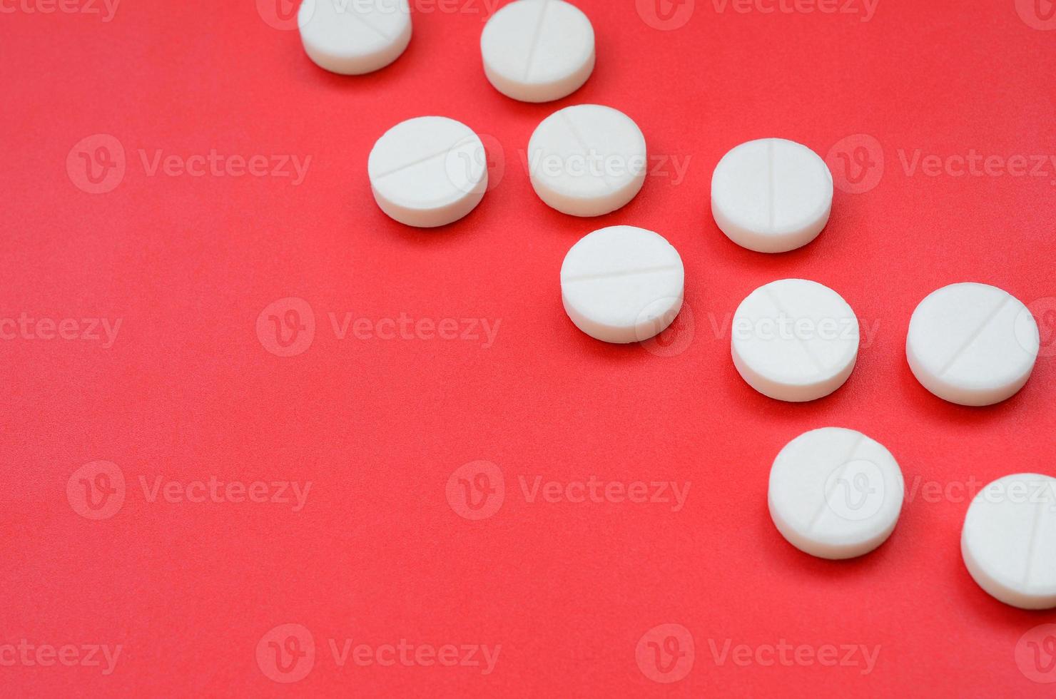 quelques comprimés blancs reposent sur une surface de fond rouge vif. image de fond sur des sujets médicaux et pharmaceutiques photo