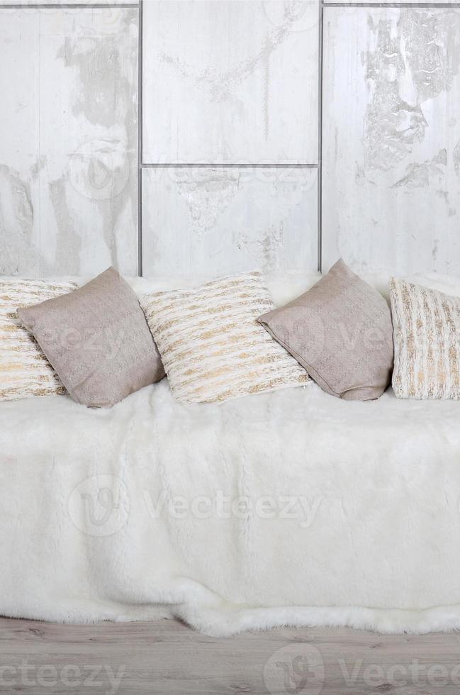 de nombreux oreillers reposent sur le canapé, qui est recouvert d'un grand voile en peluche sur le fond d'un mur de marbre photo