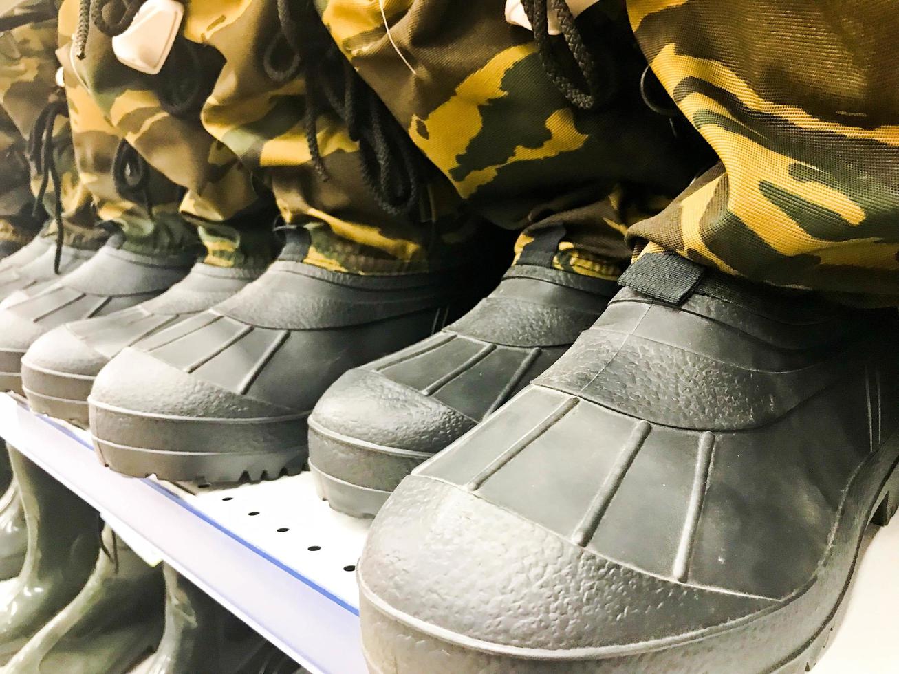 bottes en caoutchouc pour hommes militaires, chaussures aux couleurs protectrices kaki toat d'affilée sur l'étagère de l'entrepôt, boutique photo