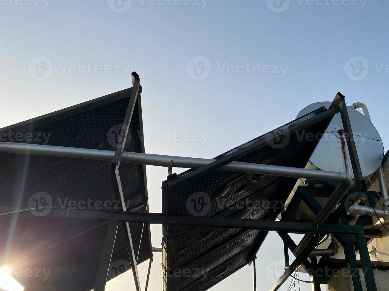 vue sur le toit d'un bâtiment dans un pays tropical chaud avec des panneaux solaires et un réservoir d'eau sur le toit. technologies écoénergétiques écoénergétiques photo