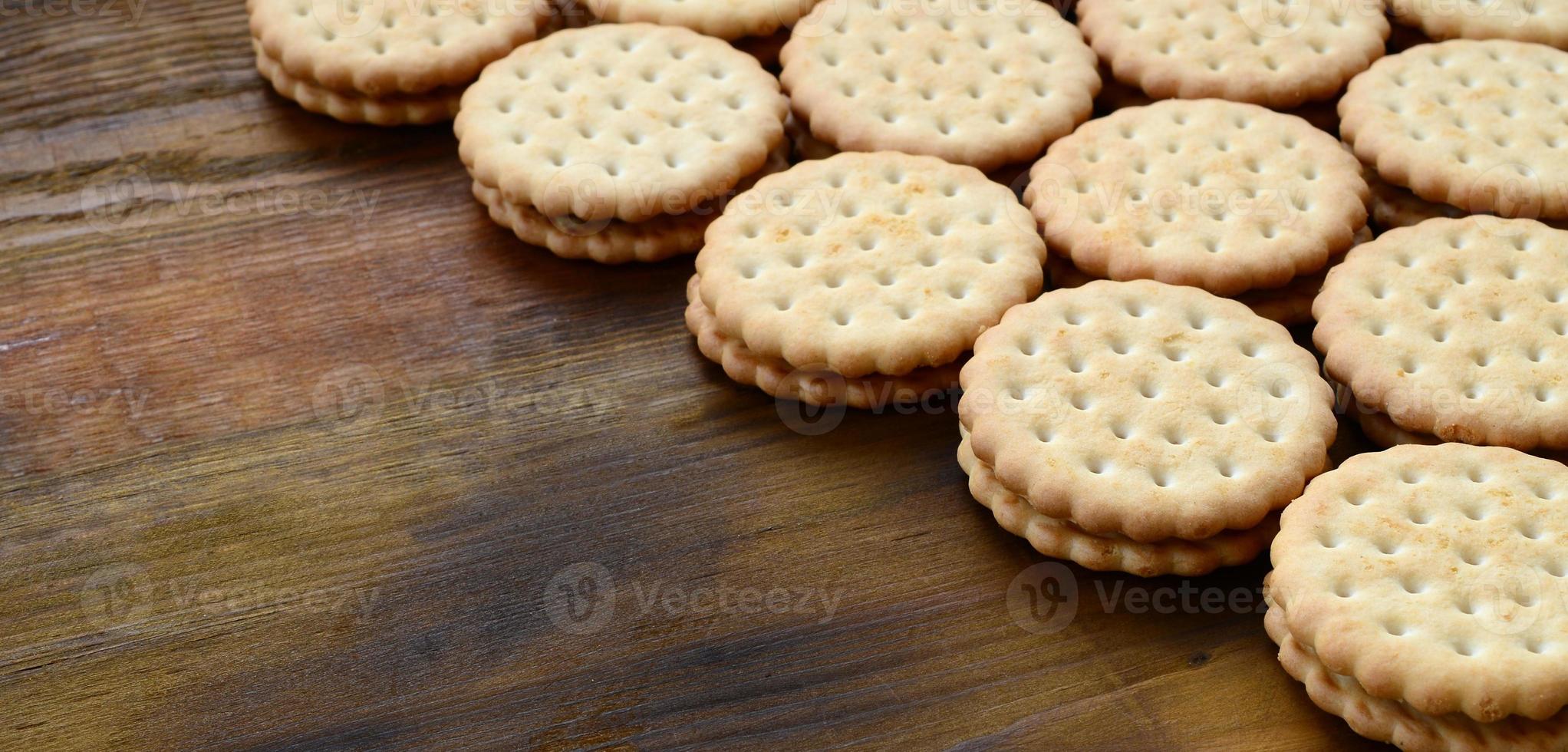 un biscuit sandwich rond fourré à la noix de coco se trouve en grande quantité sur une surface en bois marron. photo de friandises comestibles sur un fond en bois avec espace de copie