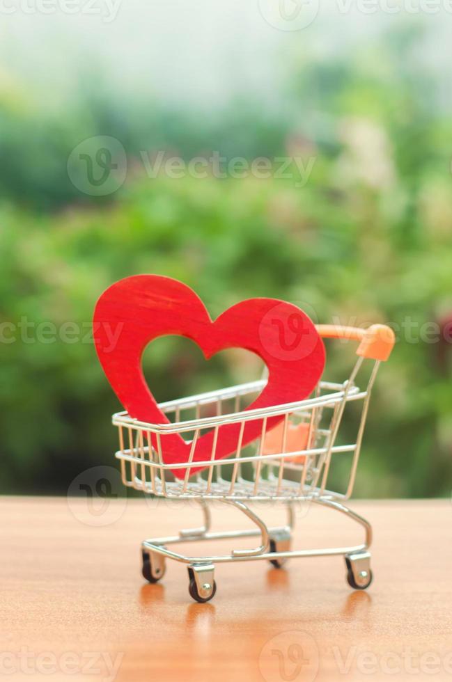 coeur en bois rouge dans le panier commercial. concept d'achat d'amour. fond naturel. soins de santé et achat de médicaments. budget de la santé. amour pour le shopping. magasin préféré. acheter l'amour et le bonheur. photo