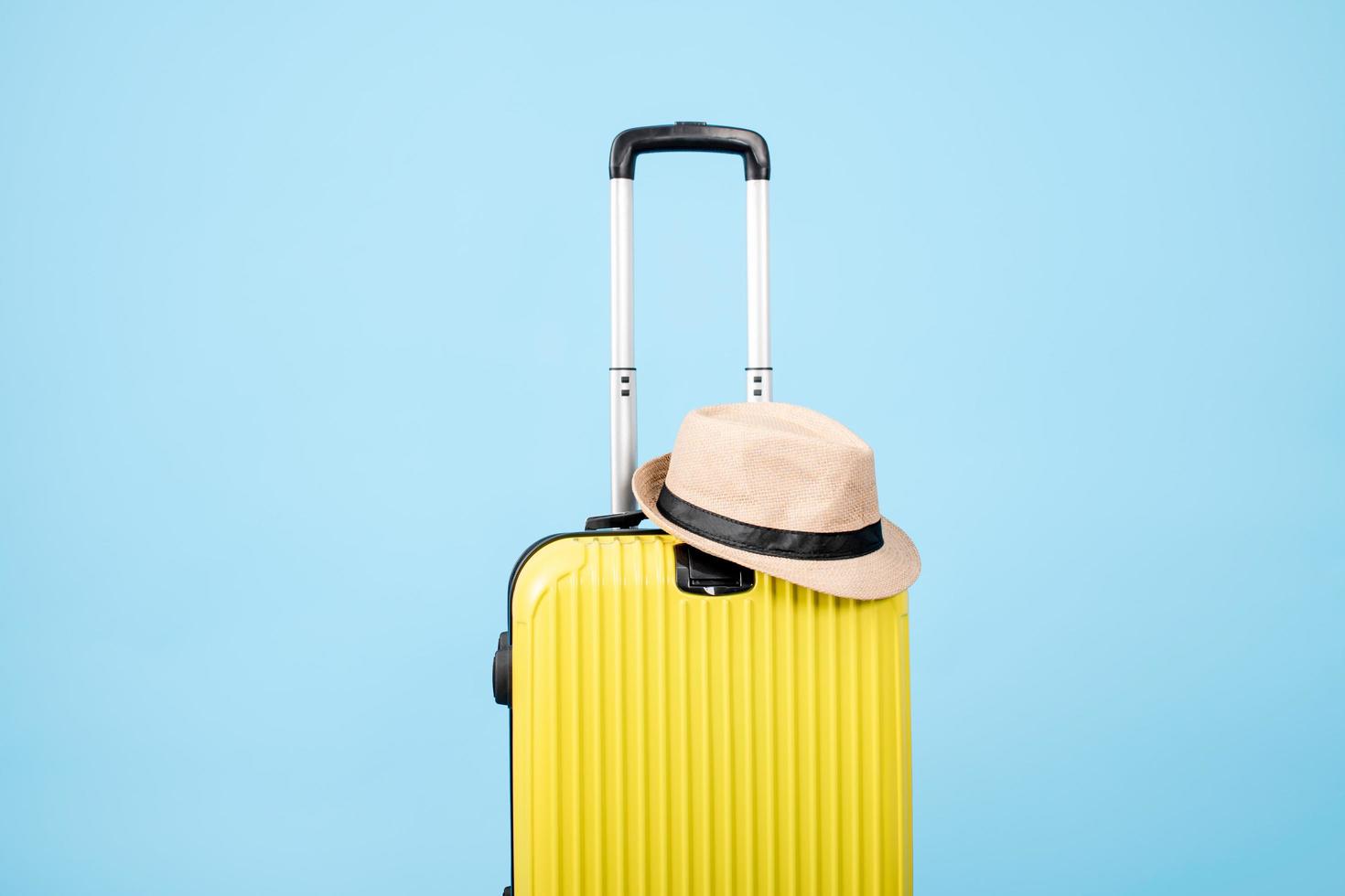 une valise jaune avec un chapeau sur fond bleu photo