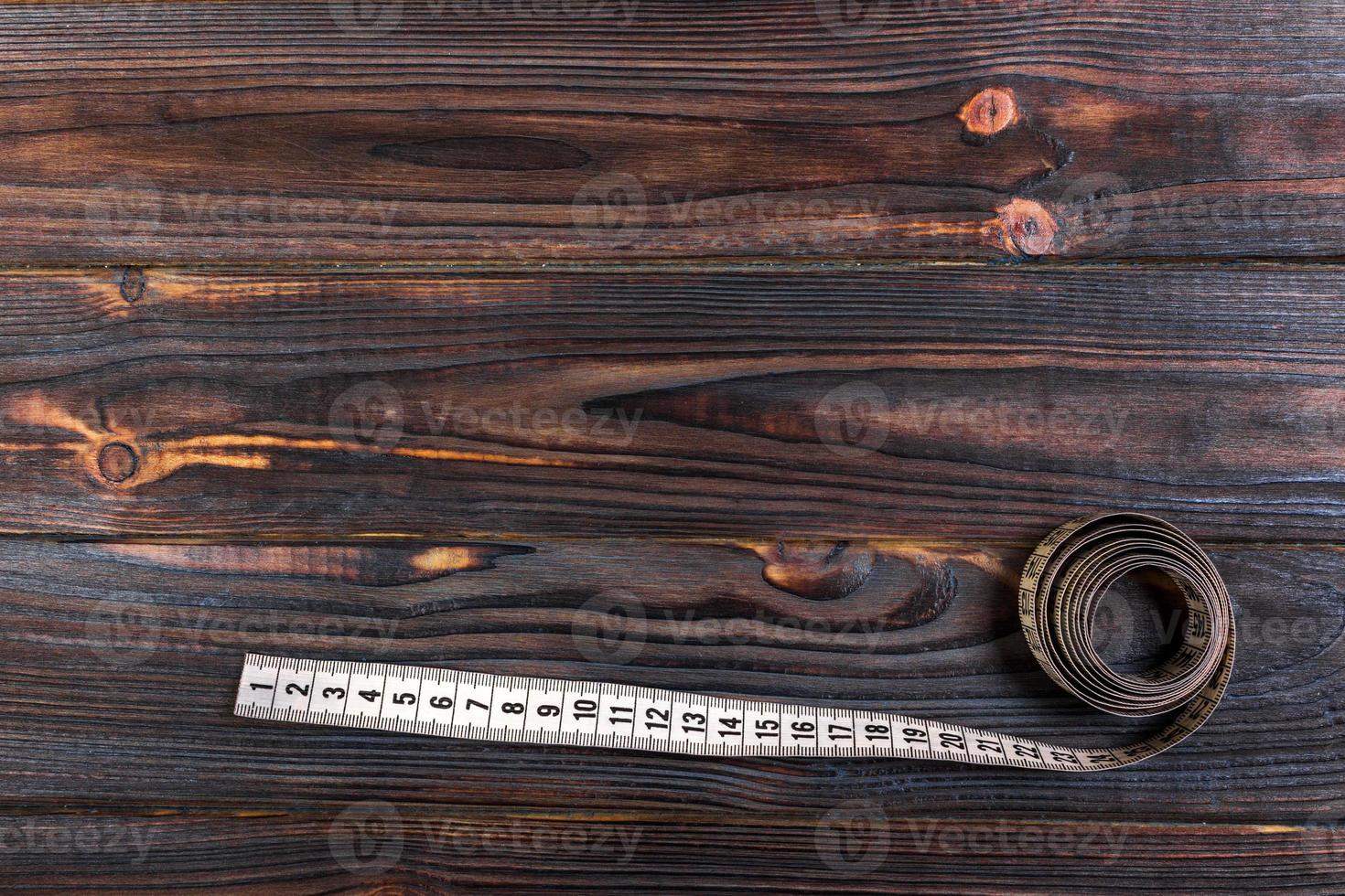 gros plan sur mesure ruban à mesurer sur fond de table en bois. ruban à mesurer blanc faible profondeur de champ photo