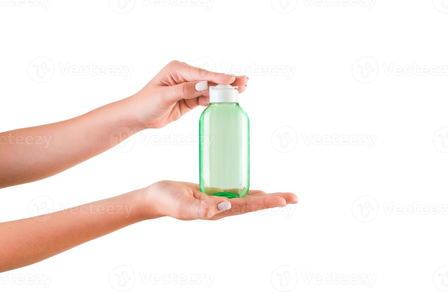 main féminine tenant une bouteille de crème de lotion isolée. fille donne des produits cosmétiques sur fond blanc photo