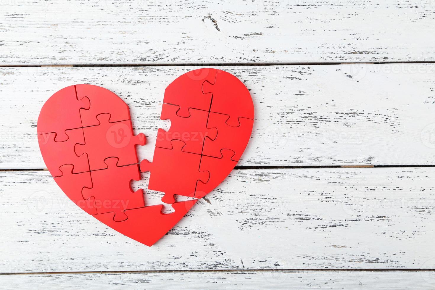 Coeur de puzzle rouge sur fond en bois blanc photo