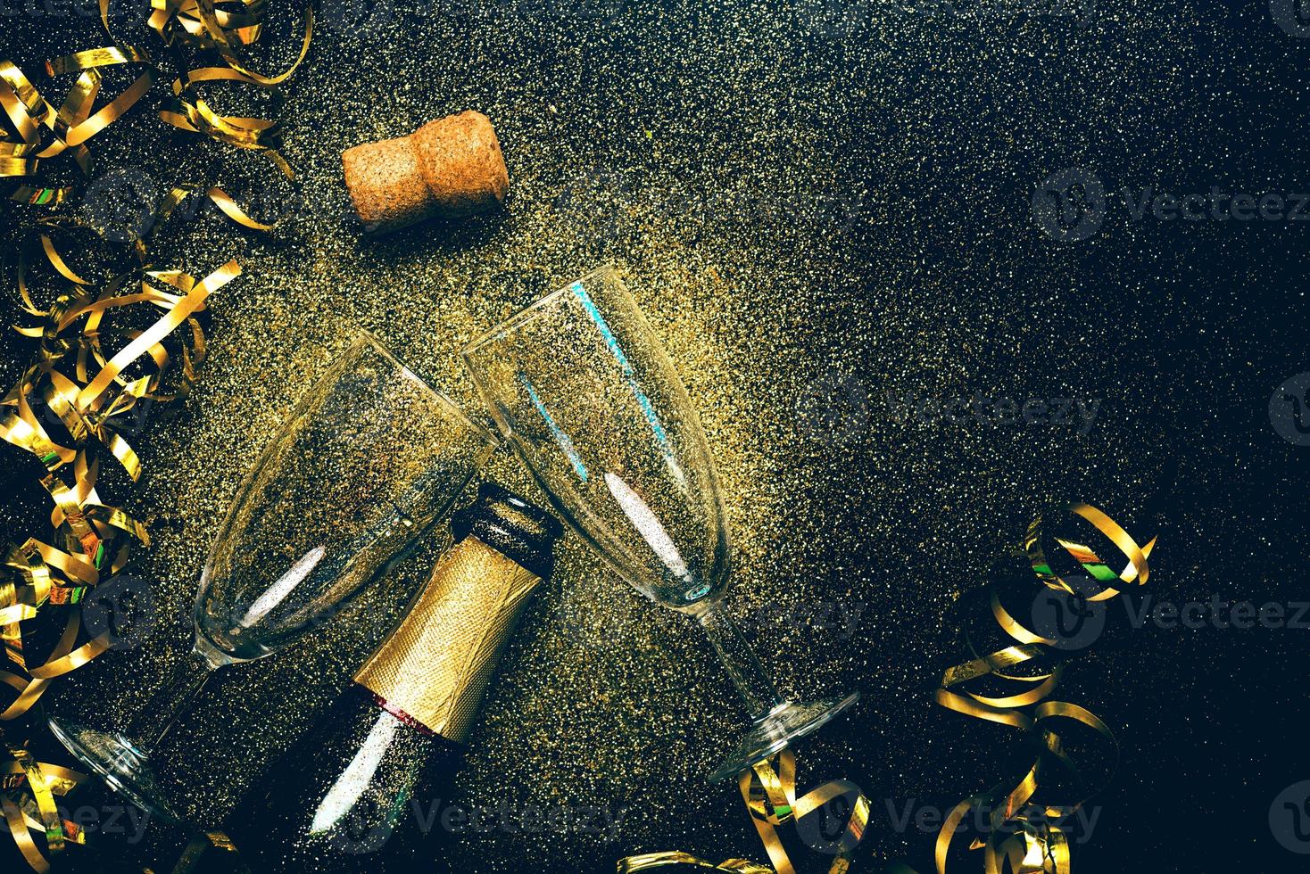 bonne année. bouteille de champagne avec deux verres, banderoles dorées et paillettes scintillantes avec espace de copie. fond de concept de célébration du nouvel an photo