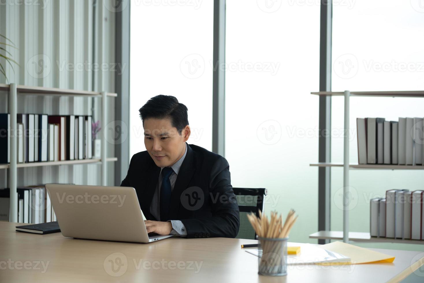 concept d'apprentissage, de réunion, de travail et d'apprentissage en ligne en ligne. homme d'affaires asiatique décontracté étudiant un cours en ligne, se rencontrant via un ordinateur portable au bureau. photo