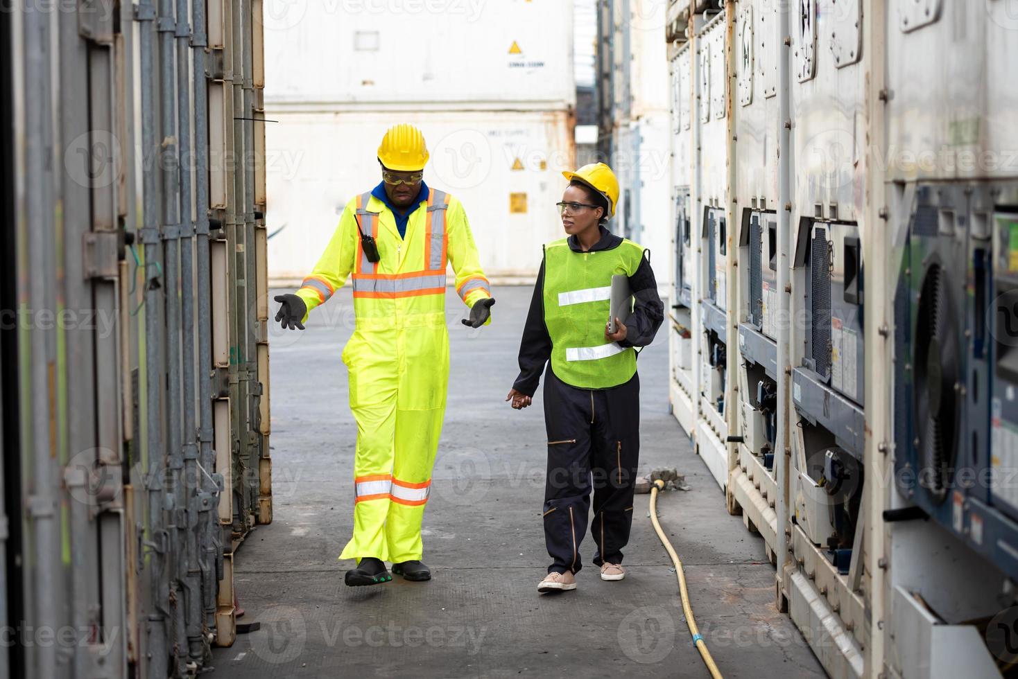 les jeunes travailleurs travaillent dans un entrepôt, des ingénieurs industriels, des superviseurs de la sécurité et des contremaîtres portant des casques et des gilets de sécurité marchant dans le dépôt du terminal de conteneurs de fret maritime. photo
