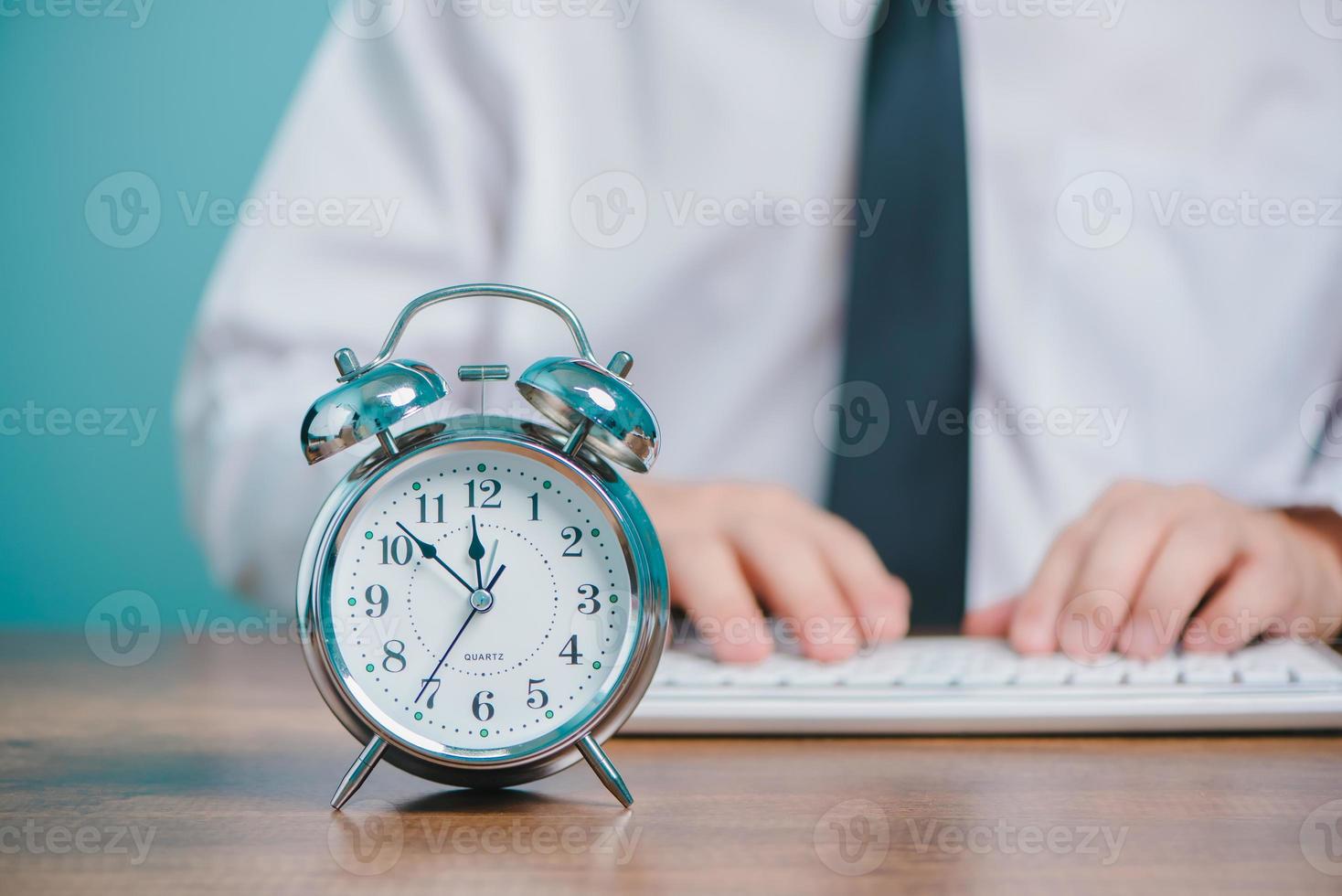 concept de temps de travail des gens d'affaires, homme d'affaires travaillant et tapant sur un ordinateur portable avec horloge sur le bureau. photo