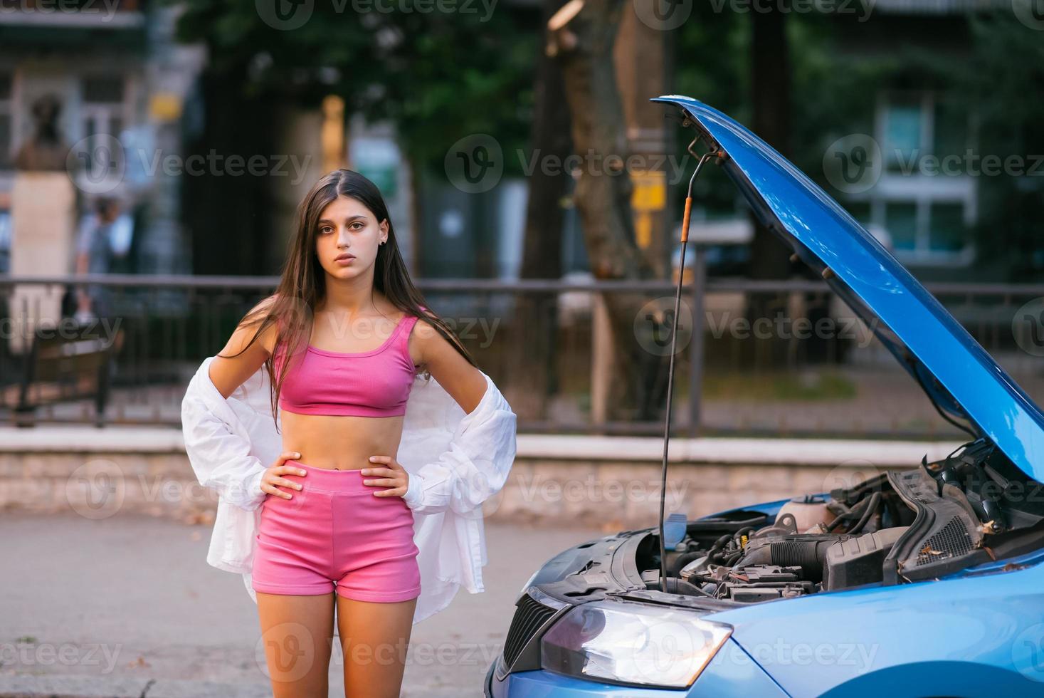 femme avec une voiture cassée sur la route. chercher de l'aide. photo