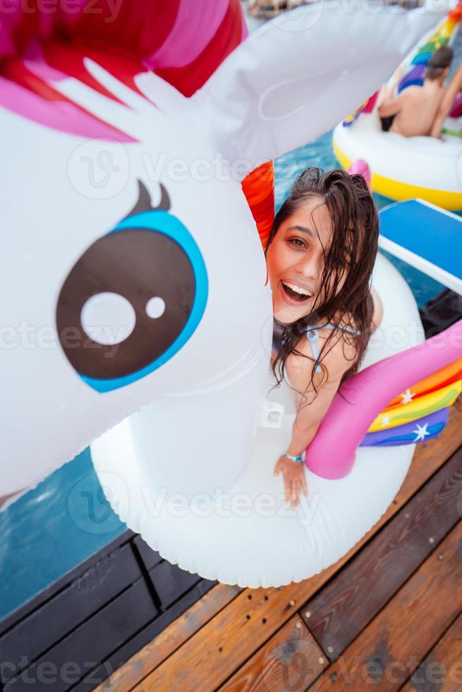 heureuse jeune femme assise sur un matelas gonflable jouet licorne photo