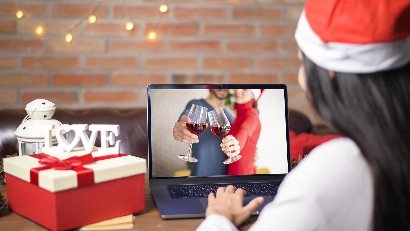 Jeune femme souriante portant un chapeau de père Noël rouge faisant appel vidéo photo