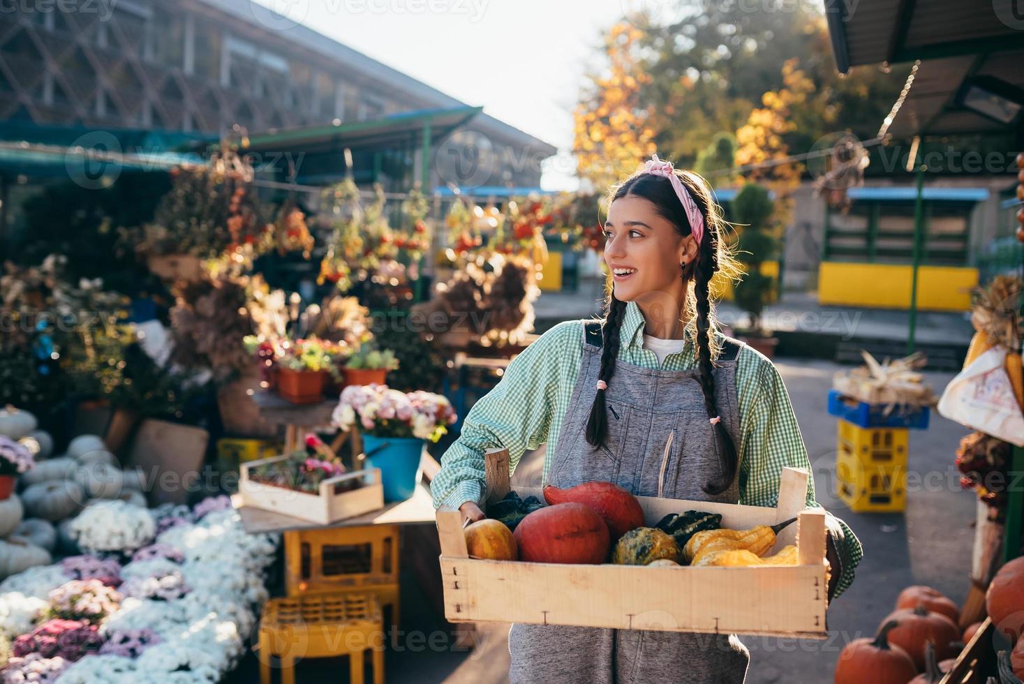 une agricultrice tient une boîte en bois avec des citrouilles dans les mains photo