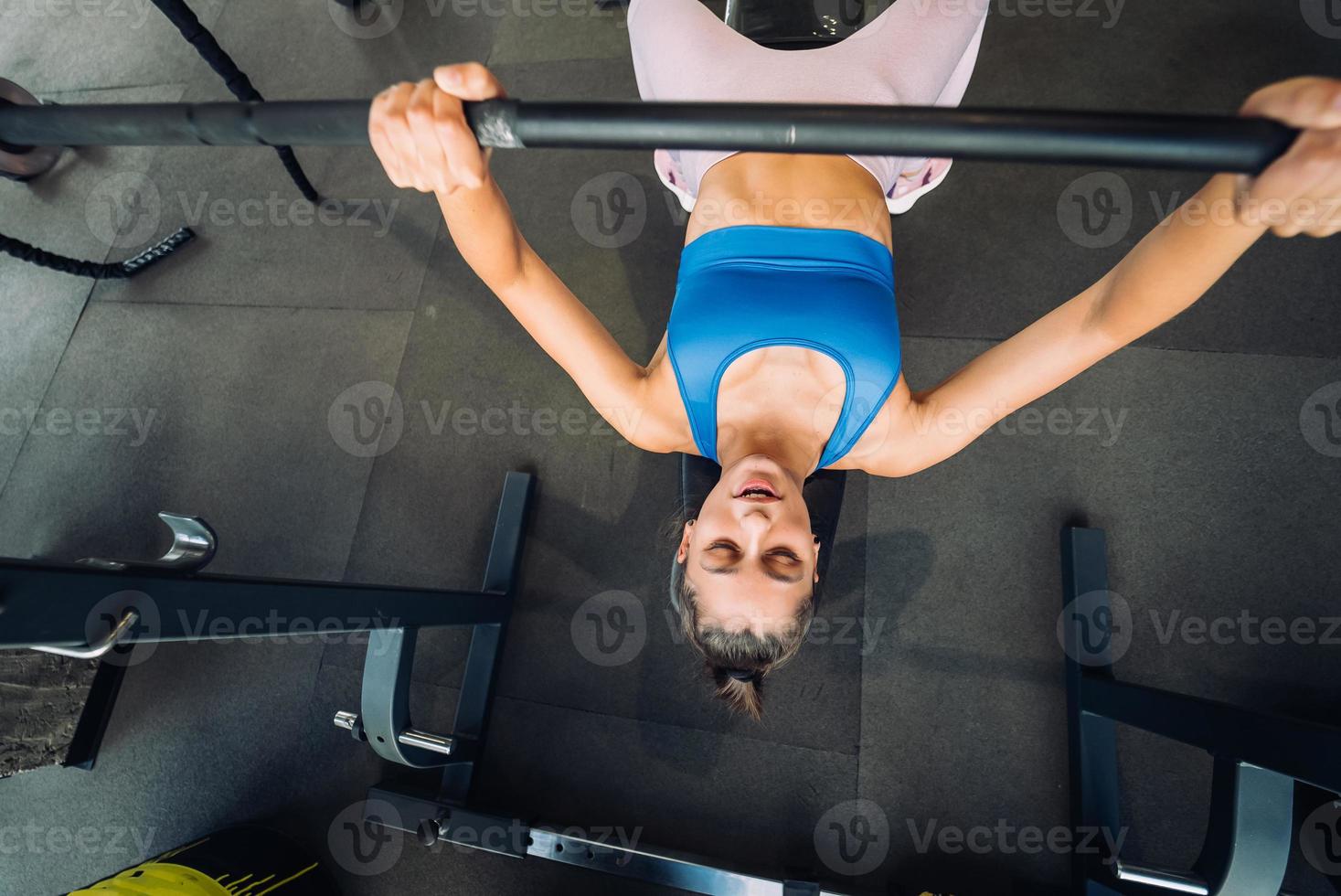 femme faisant des exercices avec des haltères sur une formation de développé couché photo