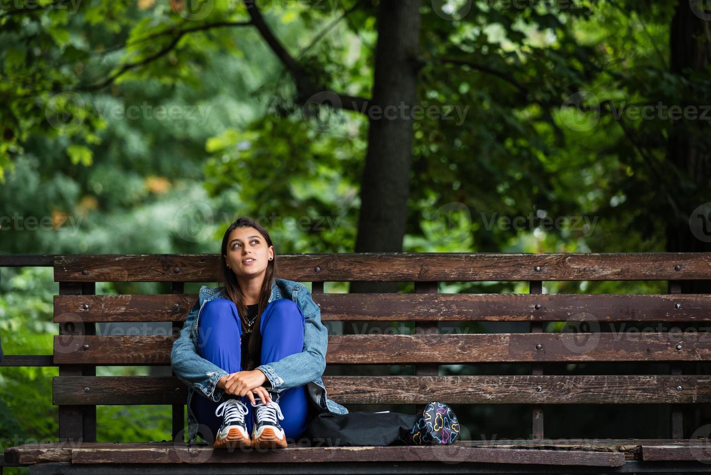 femme pensive assise sur un banc dans un parc regardant loin photo