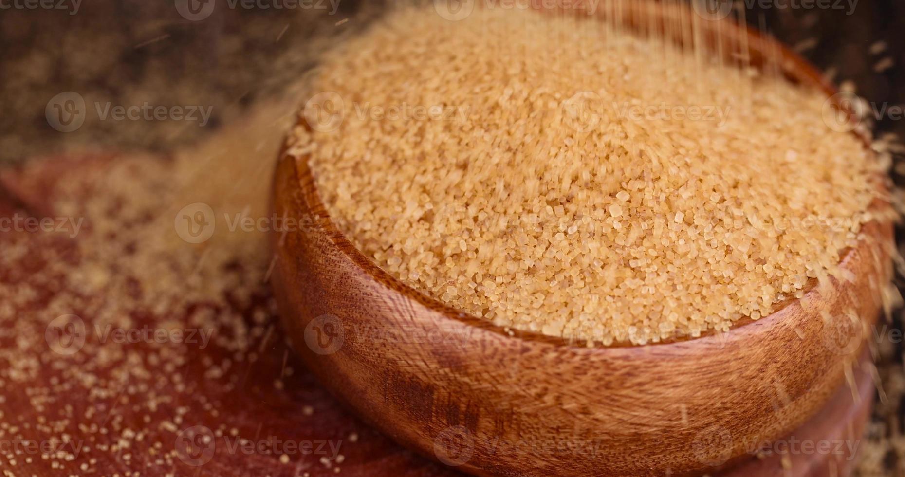 verser le sucre de canne brun naturel dans un bol en bois photo