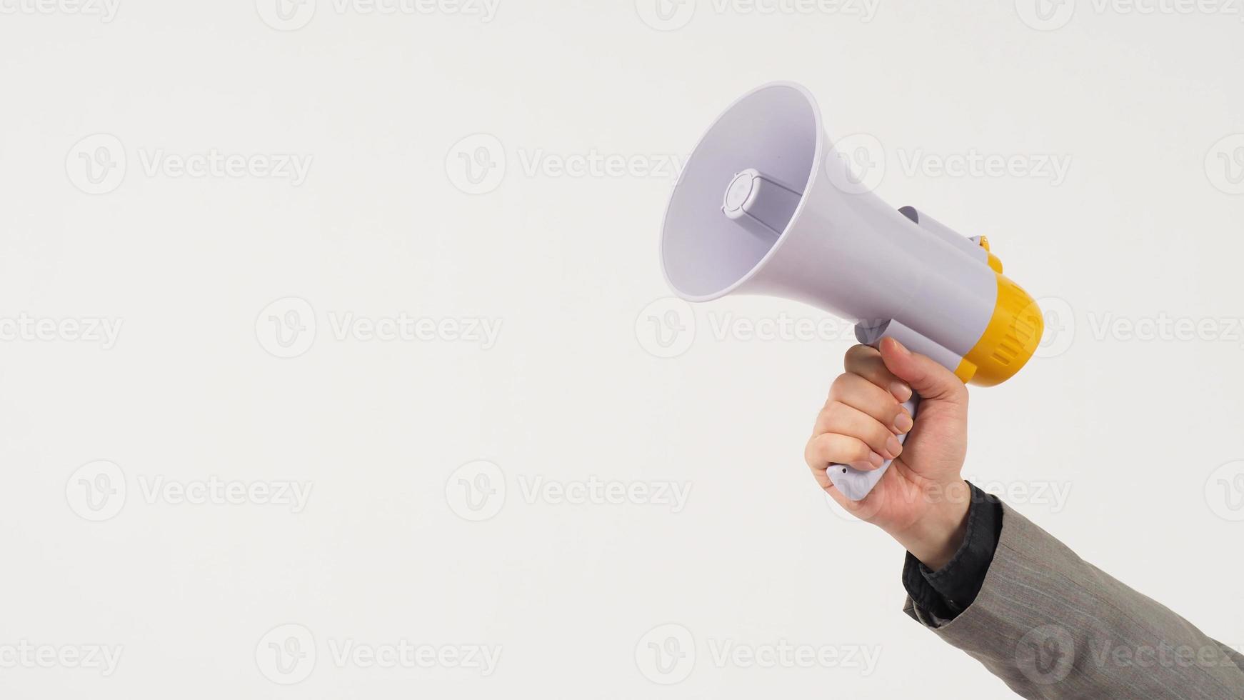 la main de l'homme tient un mégaphone et porte un costume gris sur fond blanc. photo