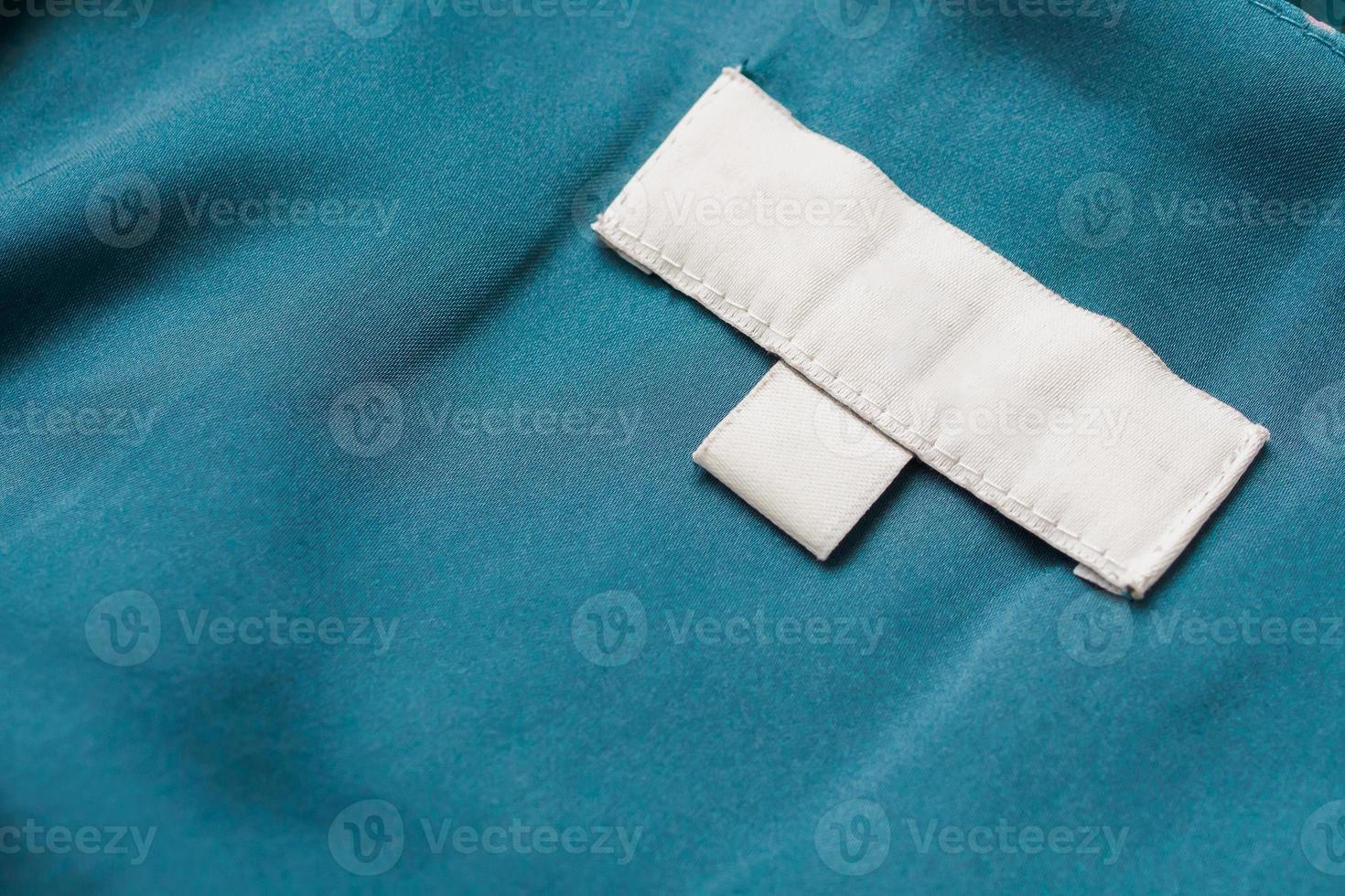 étiquette blanche de vêtements de soin de blanchisserie vierge sur fond de tissu photo