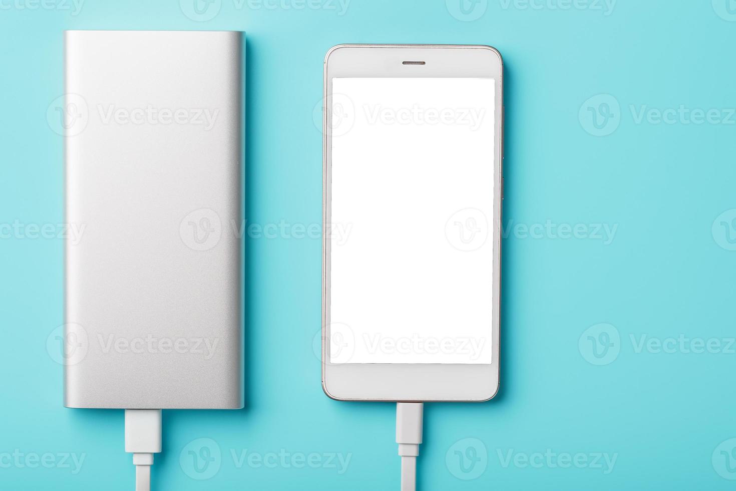 un téléphone de charge avec powerbank sur fond bleu. gardez la batterie chargée sur votre appareil où que vous alliez. photo